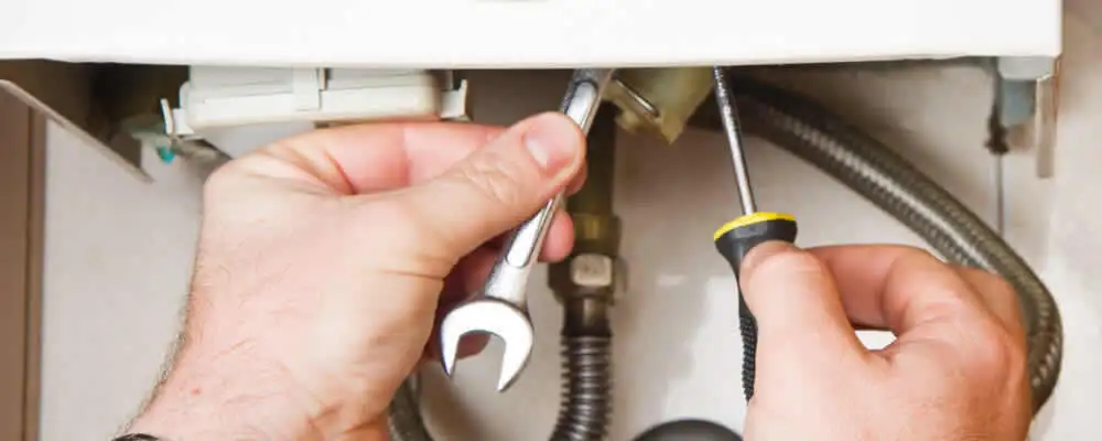 Boiler repair technician tightening pipe fittings and connections in Reading, MA