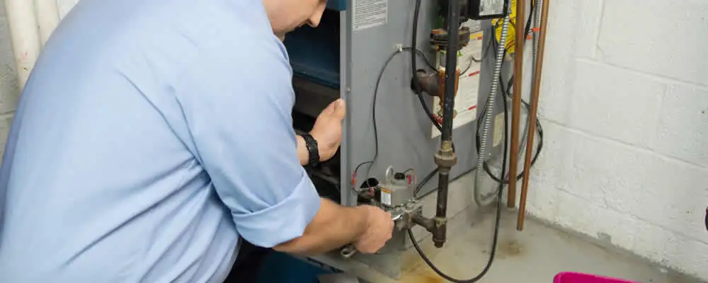 Furnace repair technician inspecting and servicing a home heating system in Reading, MA