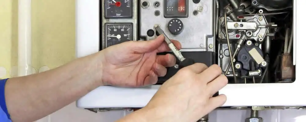 Heating repair technician adjusting boiler controls and components in Reading, MA