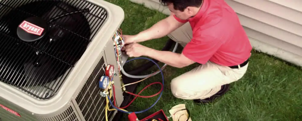 HVAC technician servicing an outdoor air conditioner unit in Reading, MA