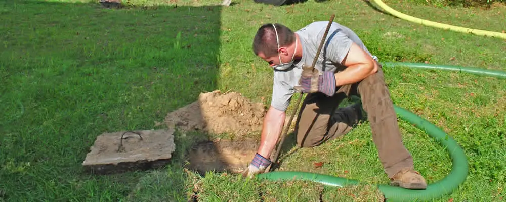 Septic pumping technician servicing a residential septic tank in Reading, MA