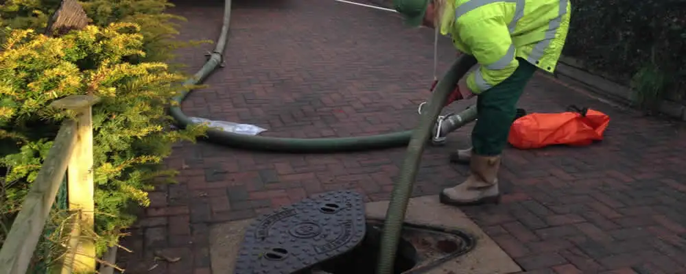 Septic tank cleaning technician servicing a septic tank with a vacuum hose in Reading, MA