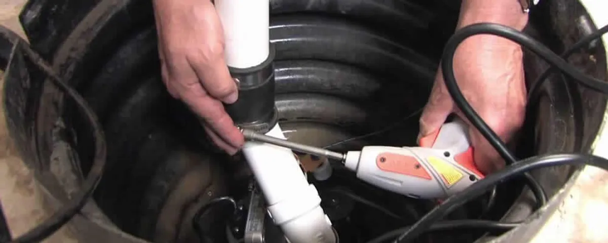 Sump pump installation technician connecting PVC discharge piping in Reading, MA