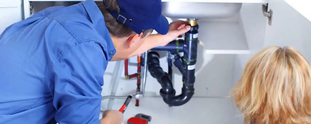Plumber repairing under-sink drain pipes and fittings in Reading, MA